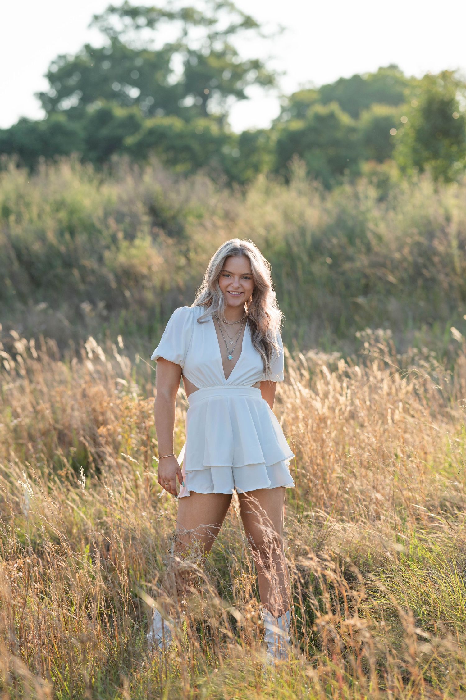 Outdoor portrait session in pink dress among tall grass during autumn.
