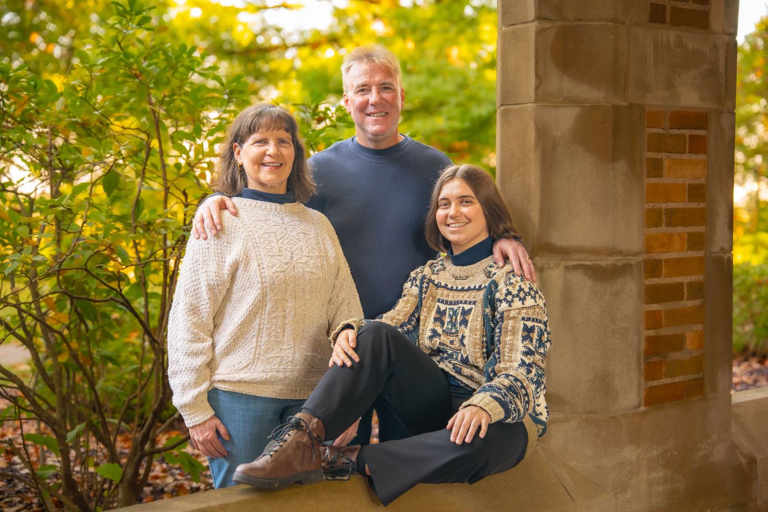 Quad Cities Family Photography. Family wearing cozy sweaters poses together on outdoor stone steps during autumn photo session.