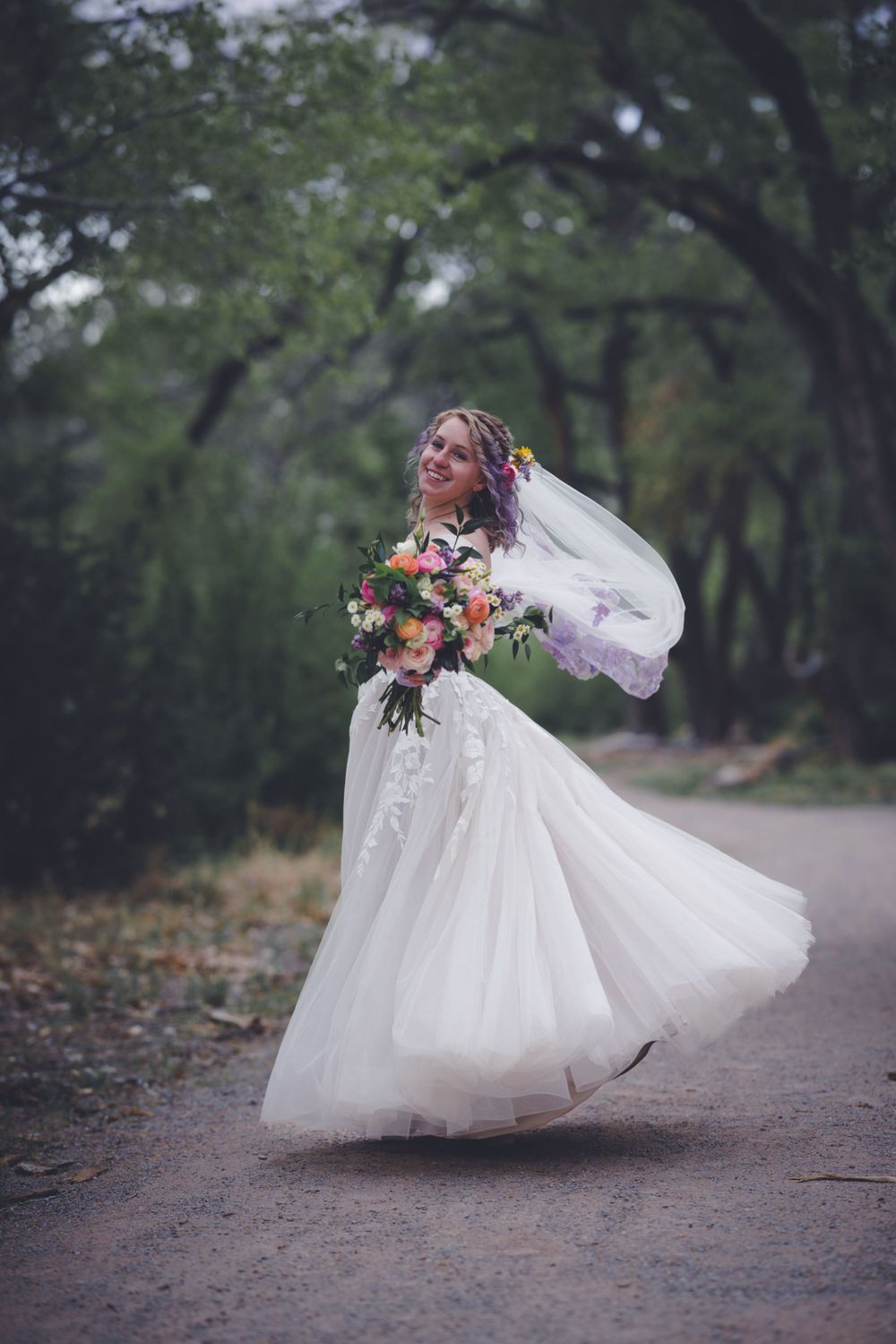 Bride in white wedding dress spinning in a forest