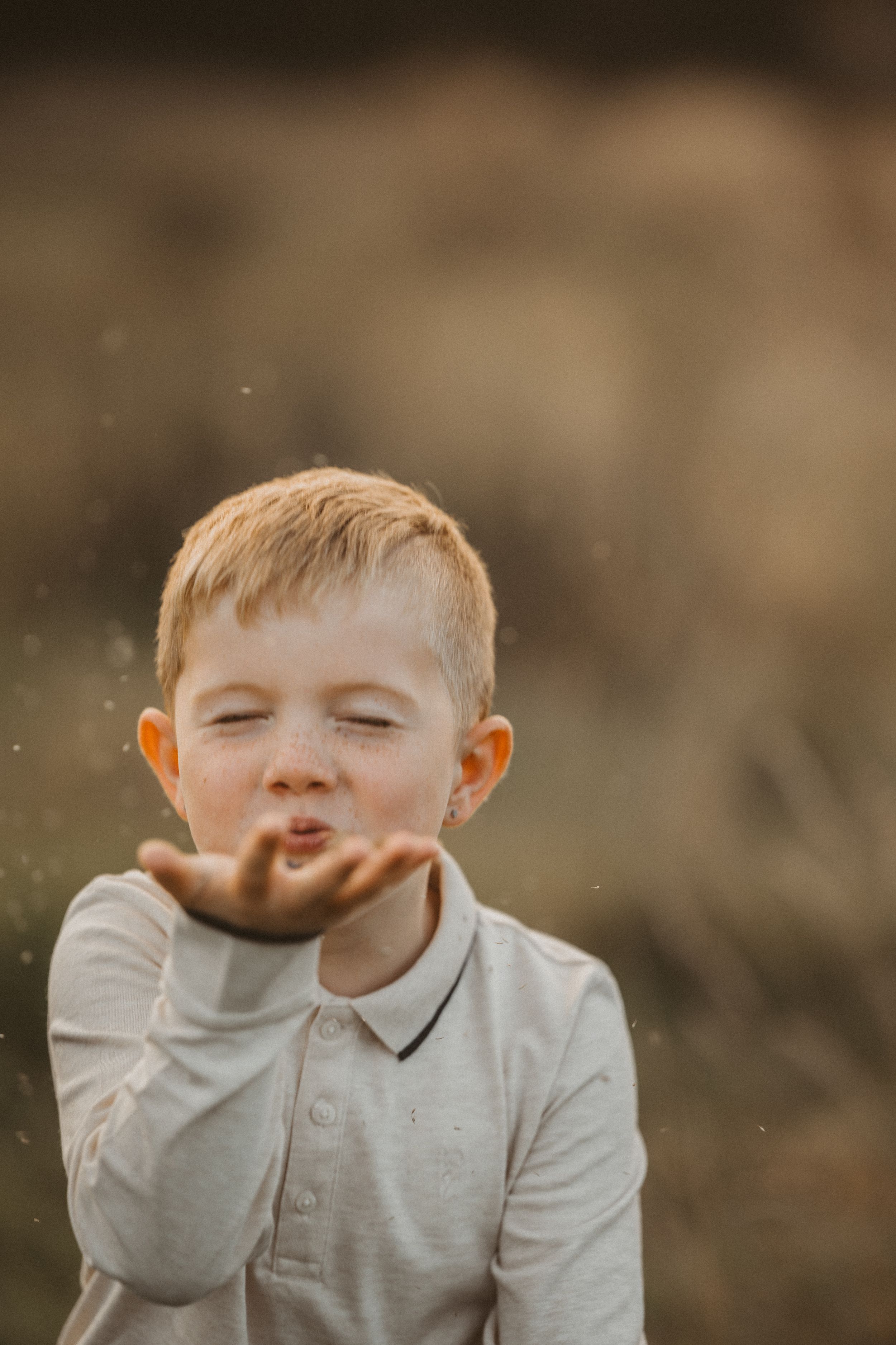 A child in a light gray shirt blowing and making playful expressions in a series of candid outdoor photos.