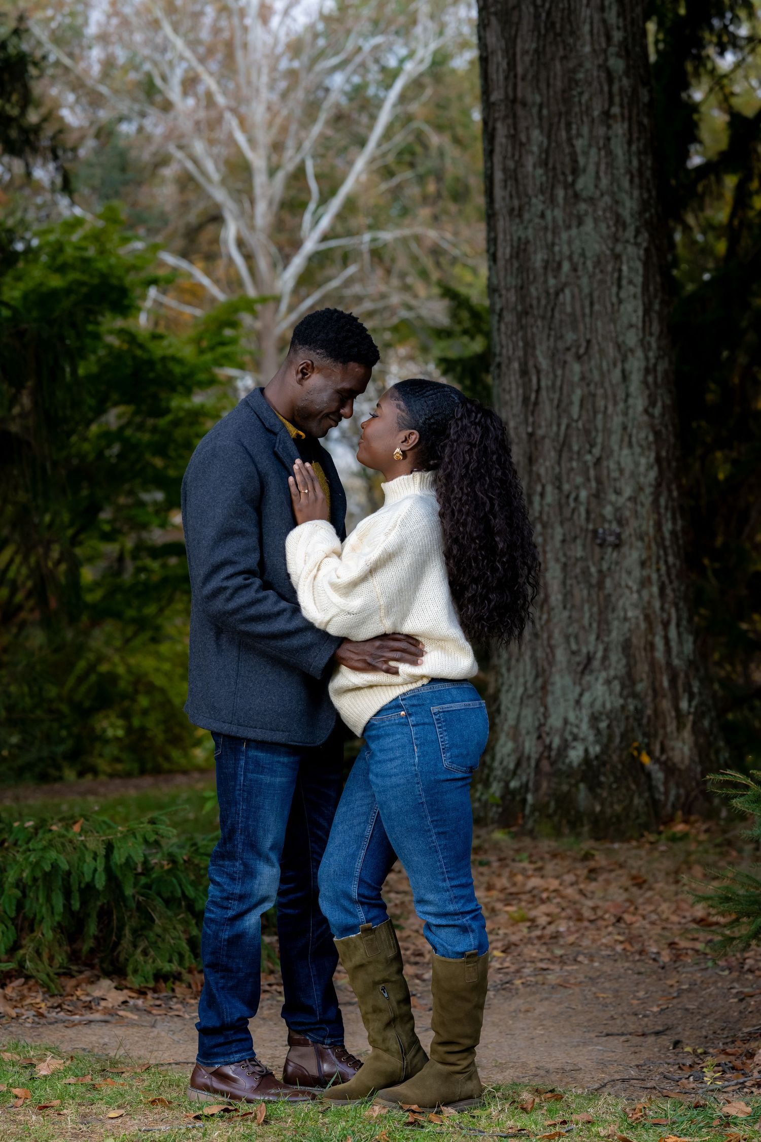 A romantic moment captured between two people in a wooded setting.