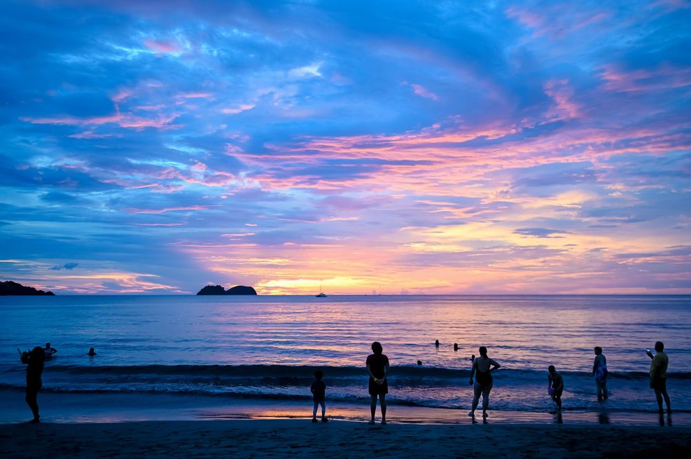 Beautiful sunset over a beach with silhouettes of people watching on the shore.
