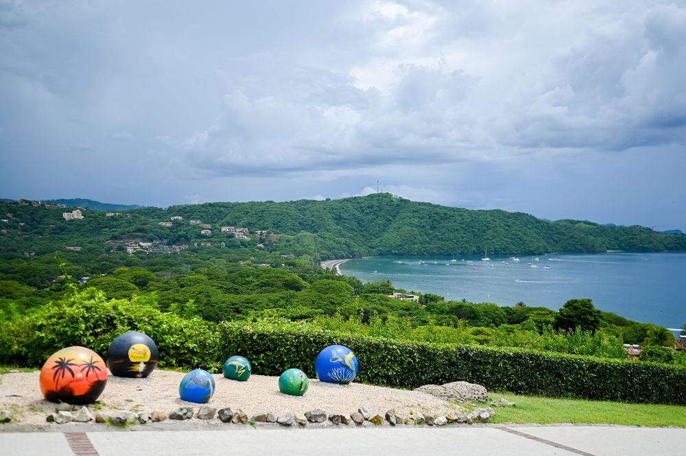 Scenic coastal landscape with green hills and ocean views under cloudy skies.