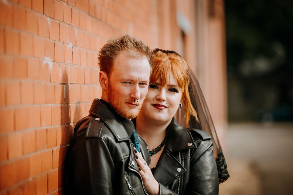 Intimate portrait of couple in coordinated black leather and gothic attire.