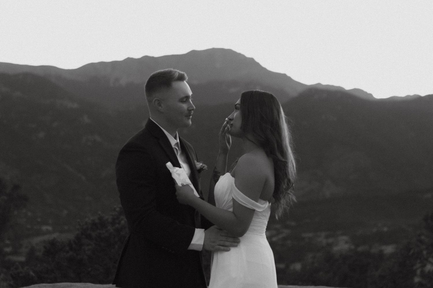 A couple in wedding attire stands together against a scenic mountain backdrop in black and white at Colorado Springs, Colorado. Elopement