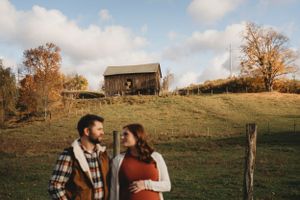 Autumn countryside scene with a rustic barn on a hill and a couple in the foreground.