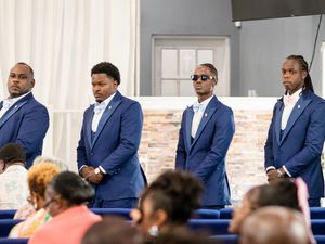Wedding party in navy blue suits lined up during formal ceremony.