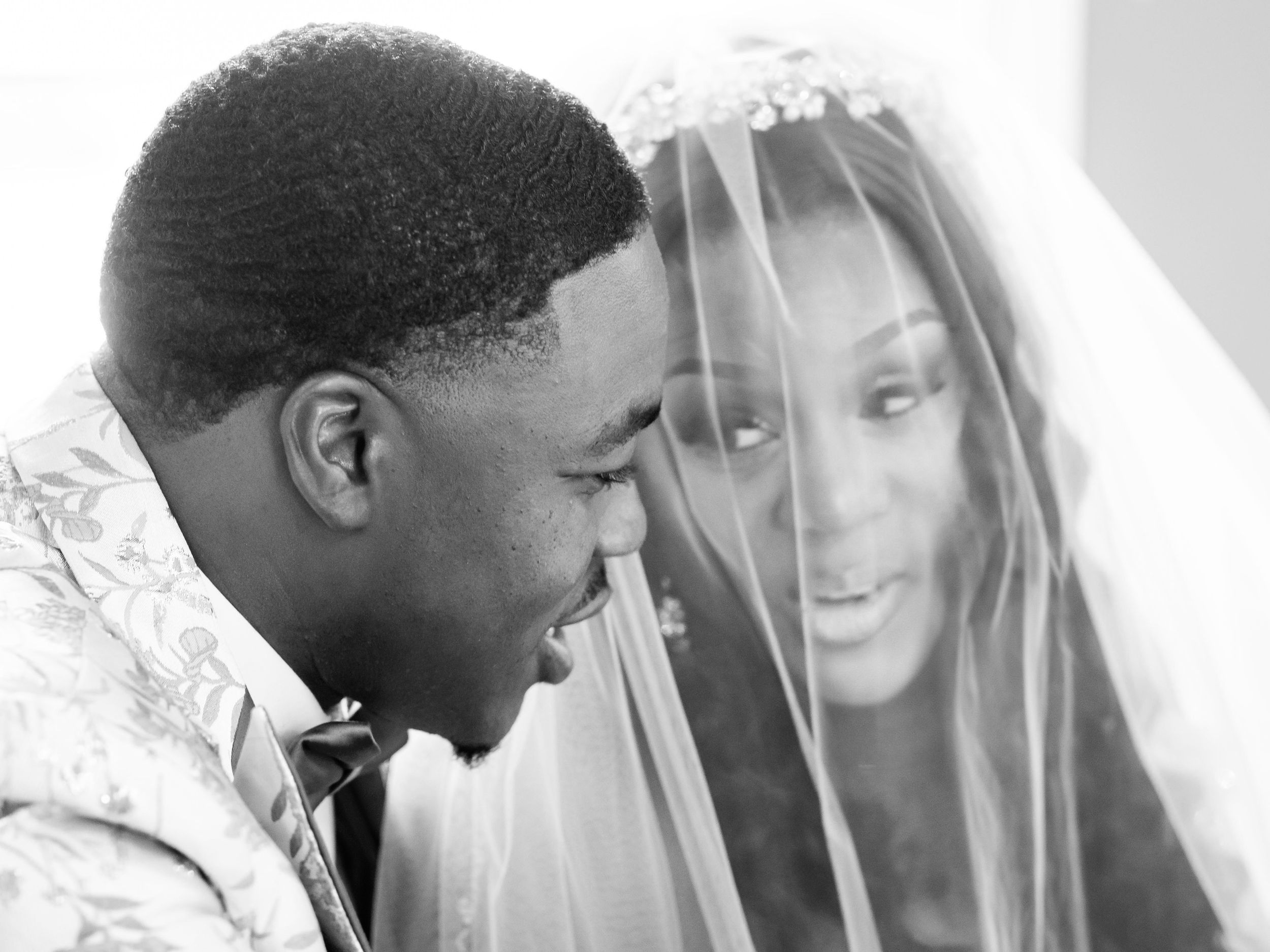 Intimate wedding photography captures through sheer veil creating dreamy effect.