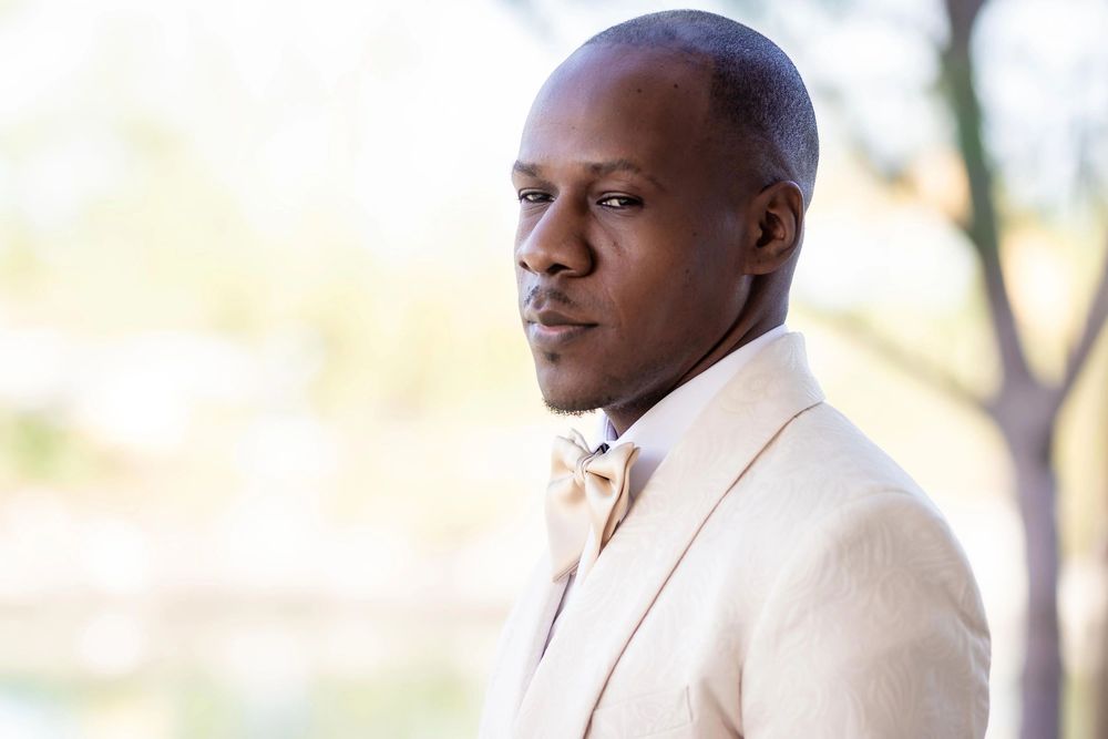 Person in cream colored suit jacket posing outdoors.