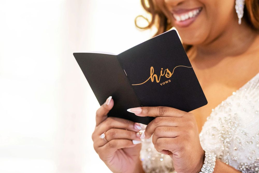 Close-up of hands holding elegant black invitation card.