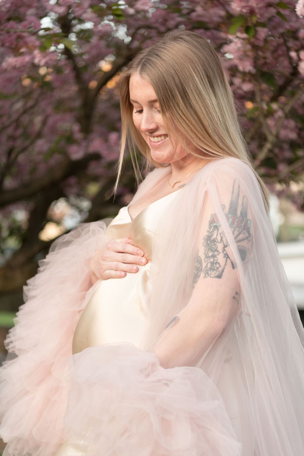 A dreamy maternity photo featuring soft pink tulle and cherry blossoms.