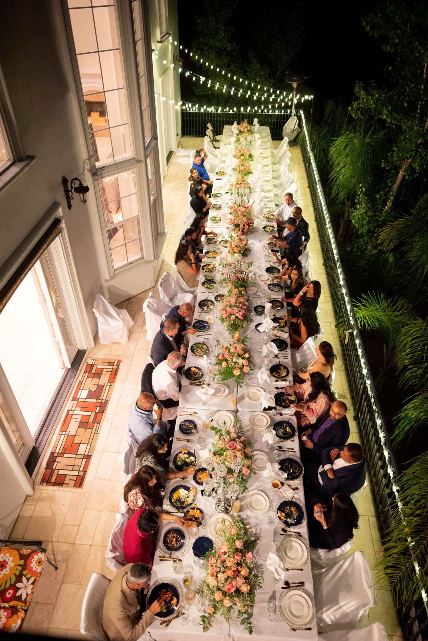 Outdoor event photography in Orange County featuring a long table dinner party with guests gathered under string lights. Candid, story-drive