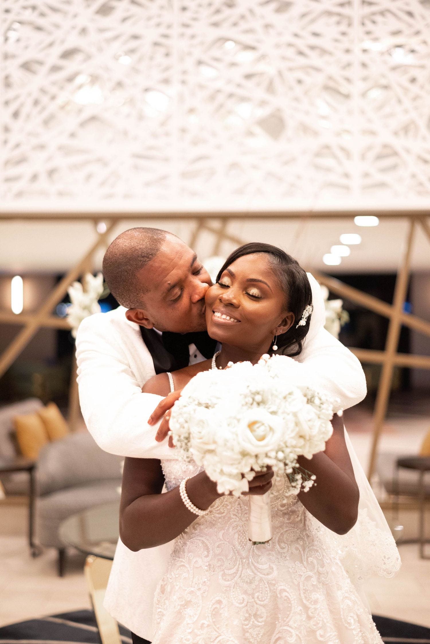 Romantic wedding photography in Orange County featuring a bride and groom embracing during an indoor ceremony. Natural, candid wedding portr