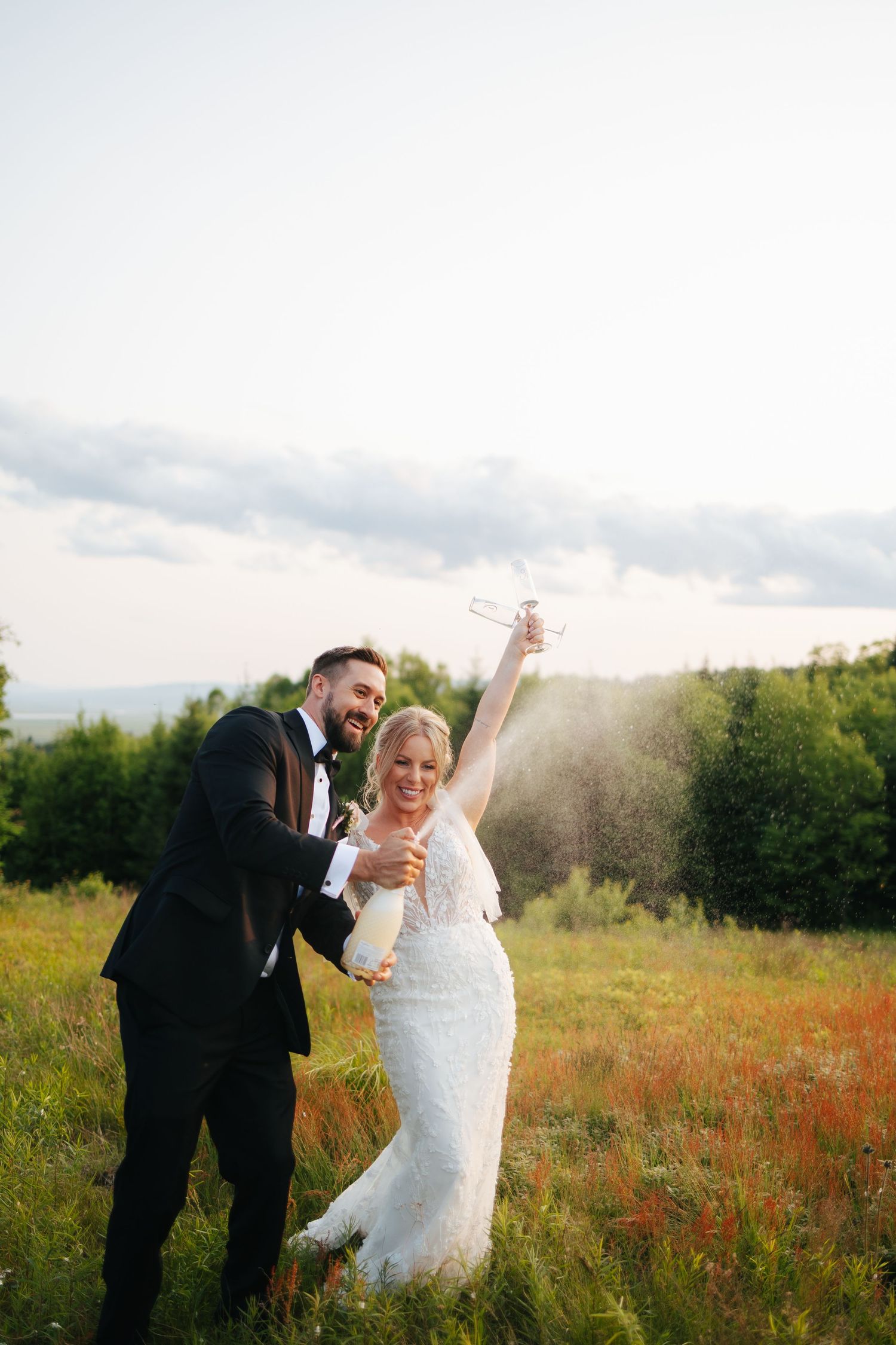 A joyful couple celebrates in a sunlit meadow with golden light.