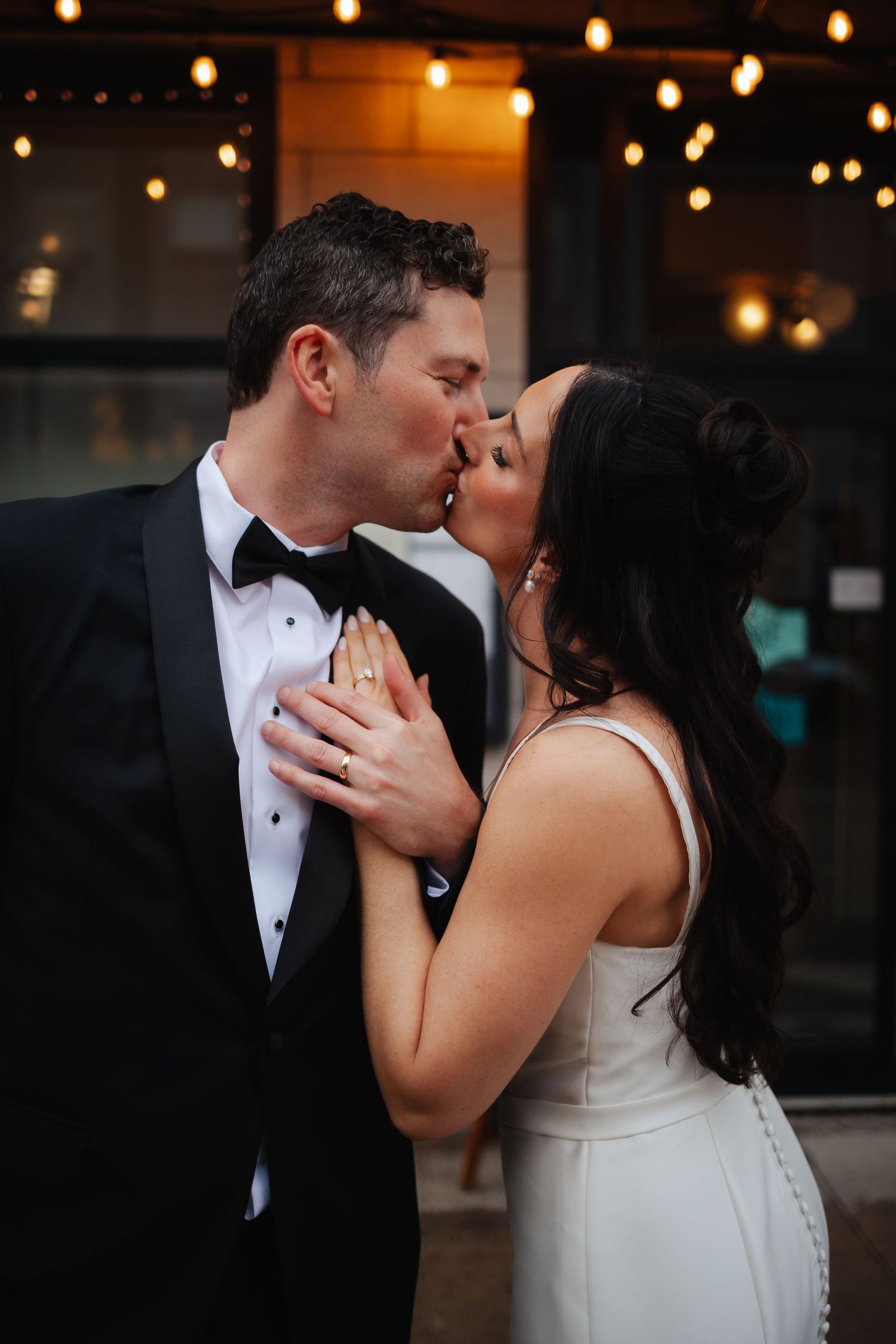 Romantic wedding dance captured under warm string lights in an intimate setting.