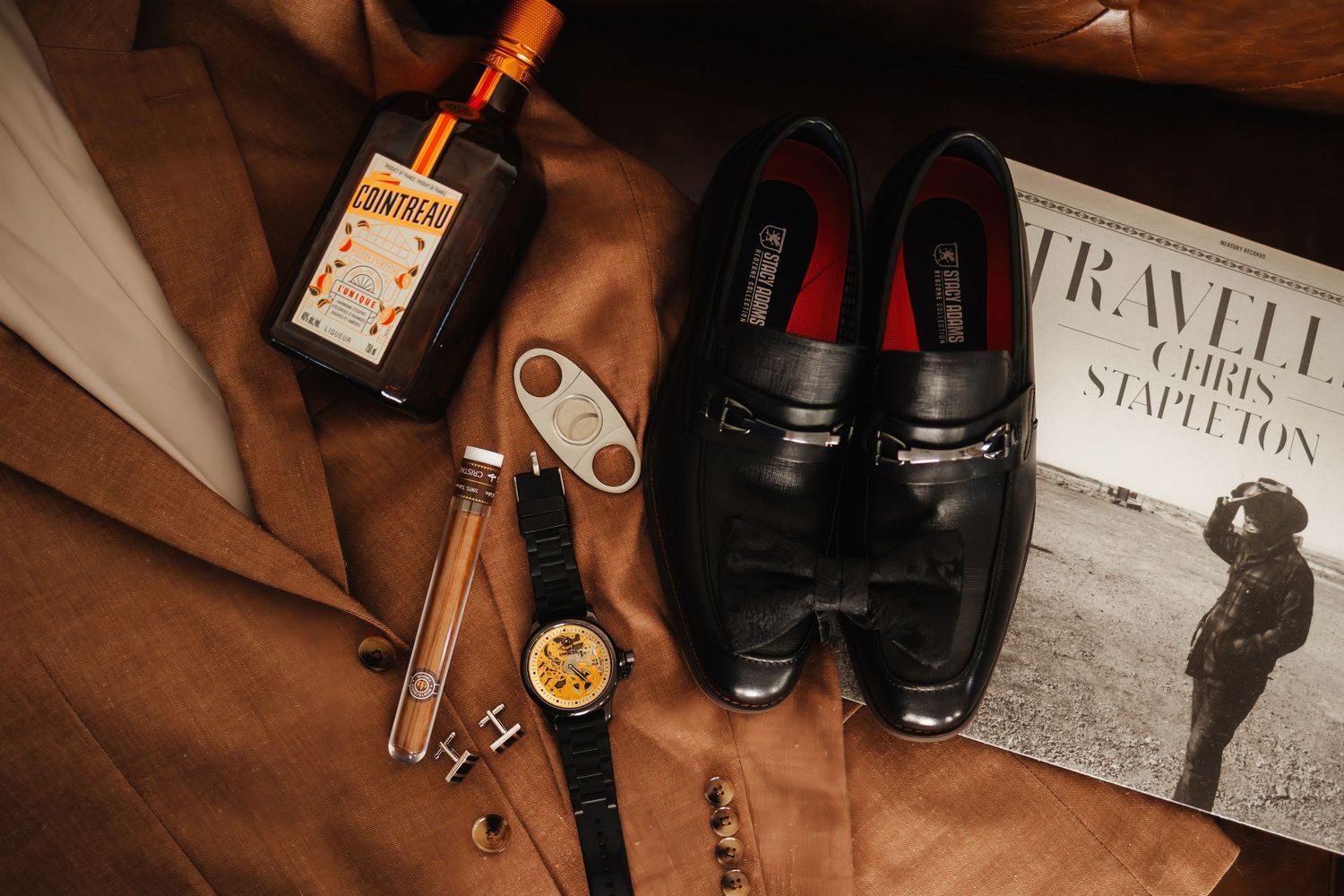 Wedding preparation items including shoes, invitations and camera equipment on rustic wooden surface.