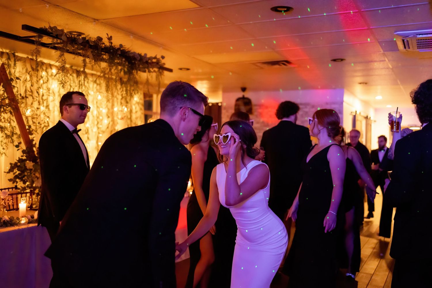 Wedding reception venue illuminated with dramatic orange and purple lighting effects.
