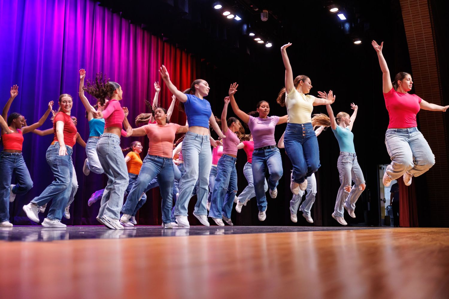 Dancers perform a dramatic lift sequence against an orange-lit stage backdrop.