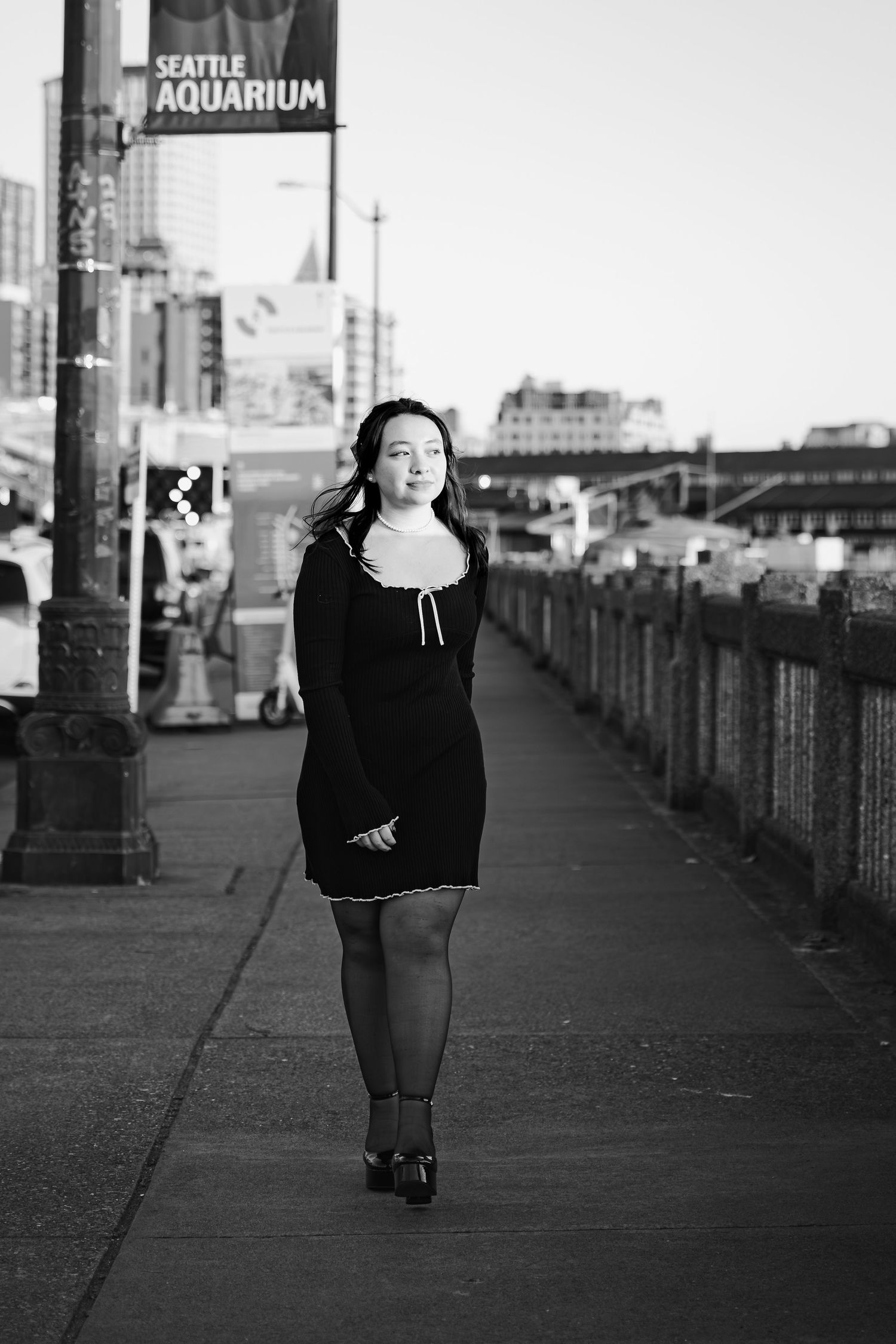 A high school senior girl looks into the sunset with Seattle skyline in the background