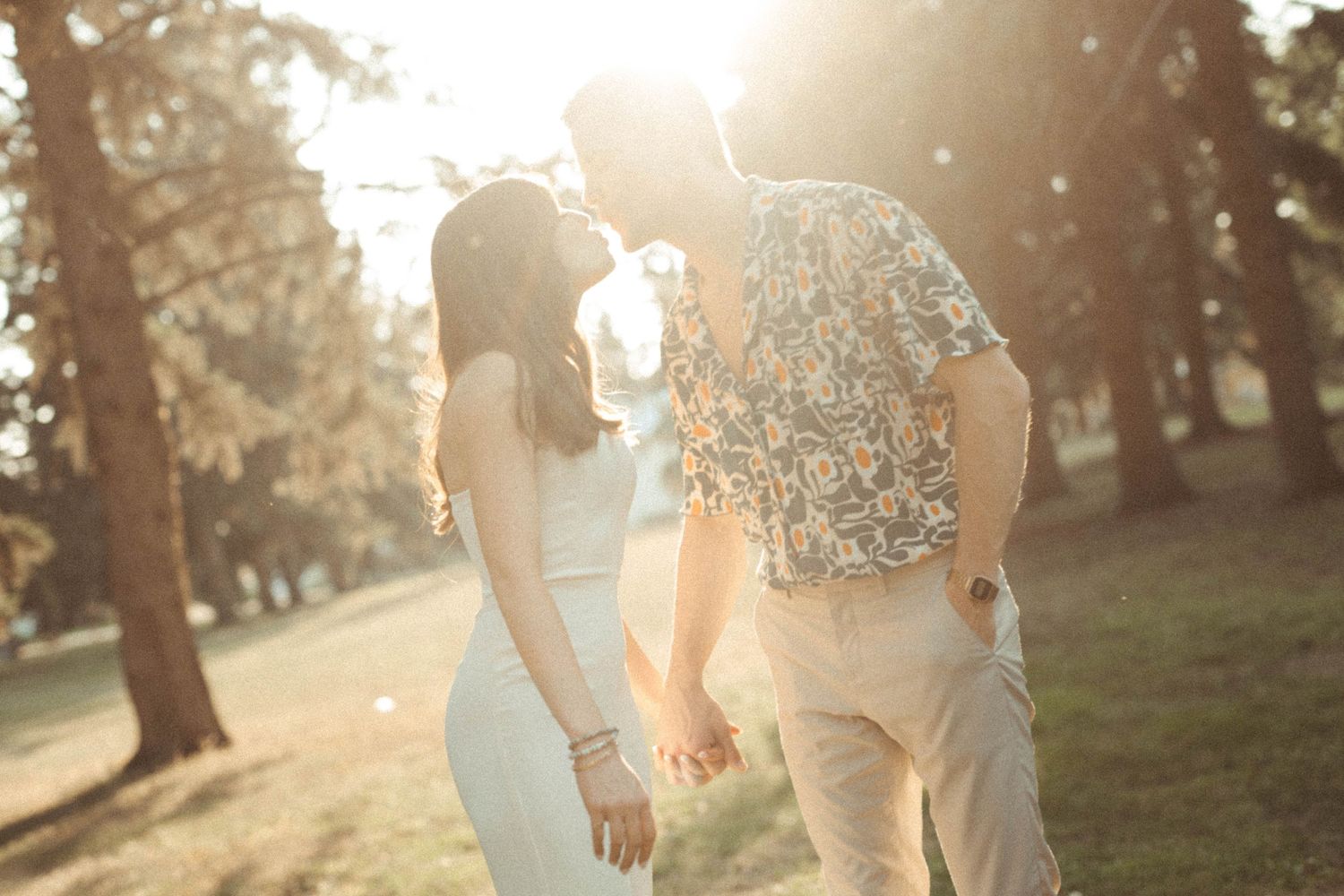 A romantic couple in wedding attire holds hands in golden sunlight while walking through a park at sunset.
Saskatoon Photographer