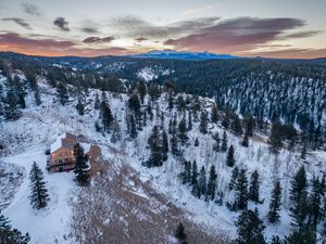 Aerial/drone shot of a luxury short term rental blanketed in snow at sunrise in Florissant, CO.