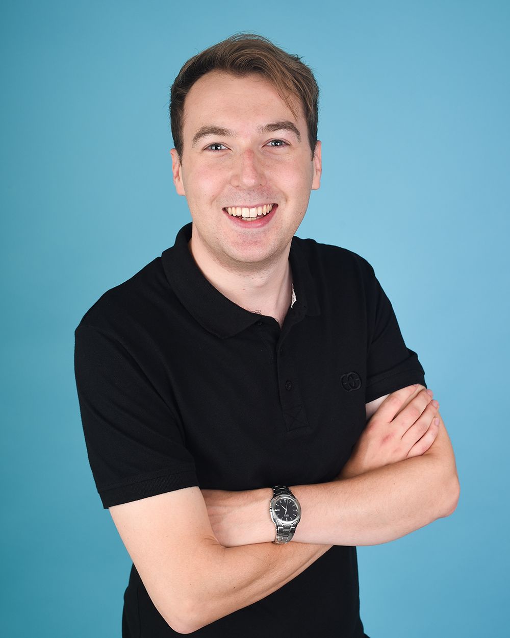 Headshot of a man in a black shirt smiling, set against an aqua blue backdrop at Abigail's Studio in Buckinghamshire.