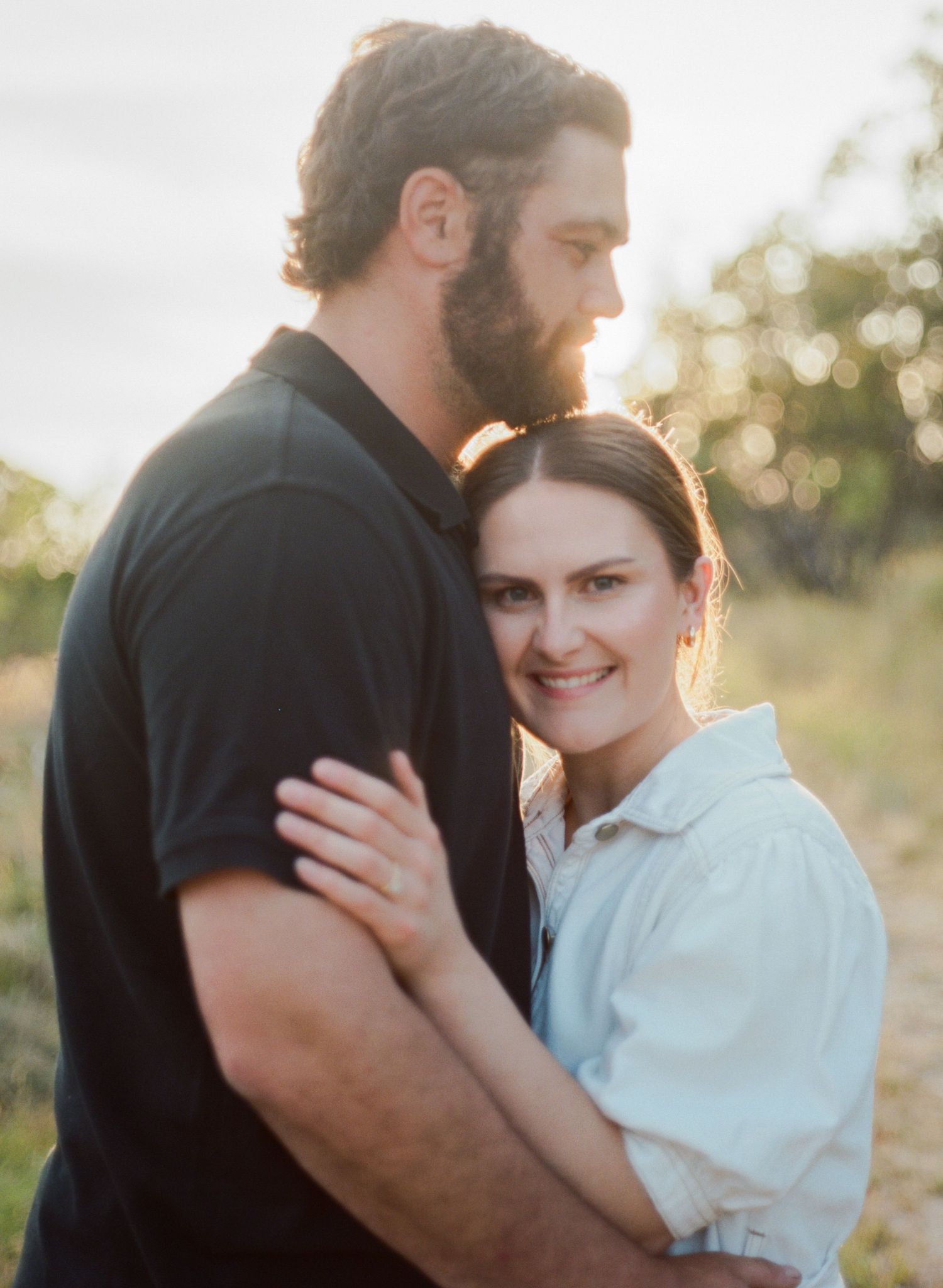 bride and groom cuddling on mountain side in golden light