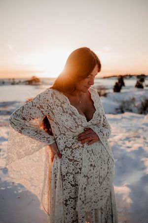 Gravid i snön med spetsklänning