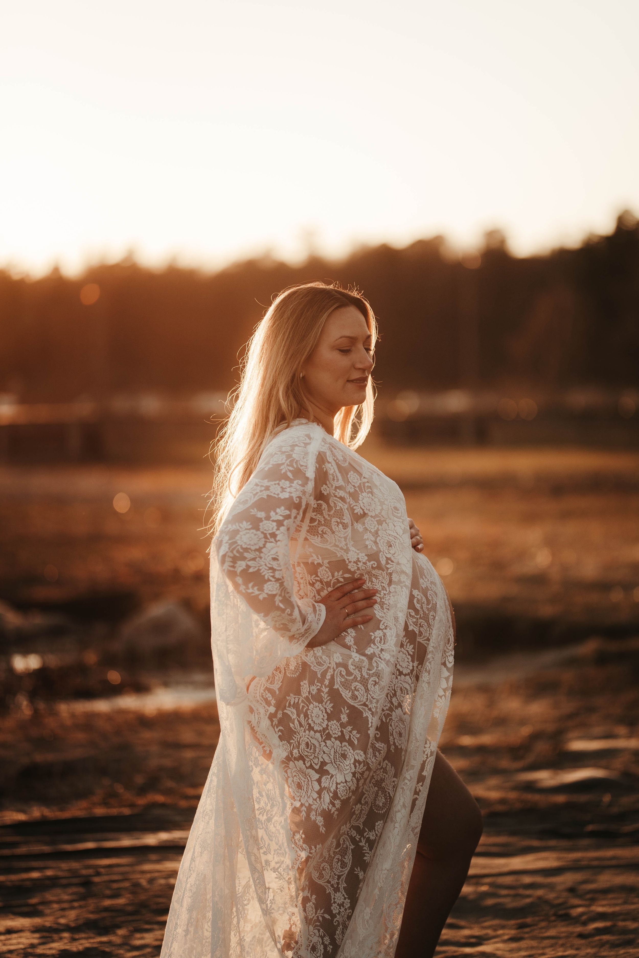 Gravid i spetsklänning i golden hour