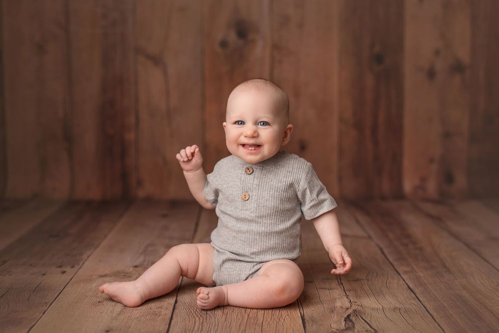 Natural studio portrait with rustic wooden backdrop and cozy gray sweater.