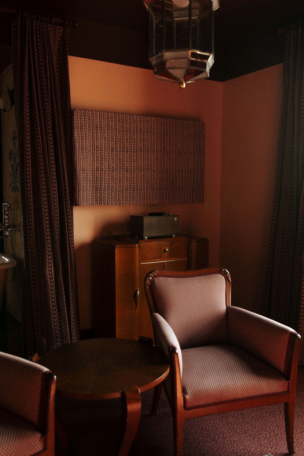 A moody vintage lounge area with brown upholstered armchair and round table in dark lighting.