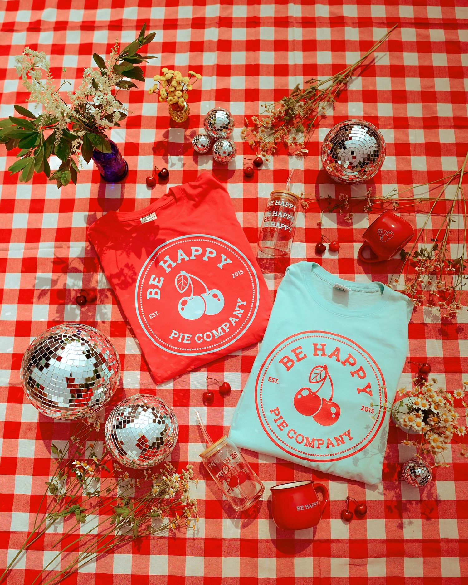 Two retro rotary phones in red and mint colors on a checkered tablecloth with silver disco balls and greenery decorations.