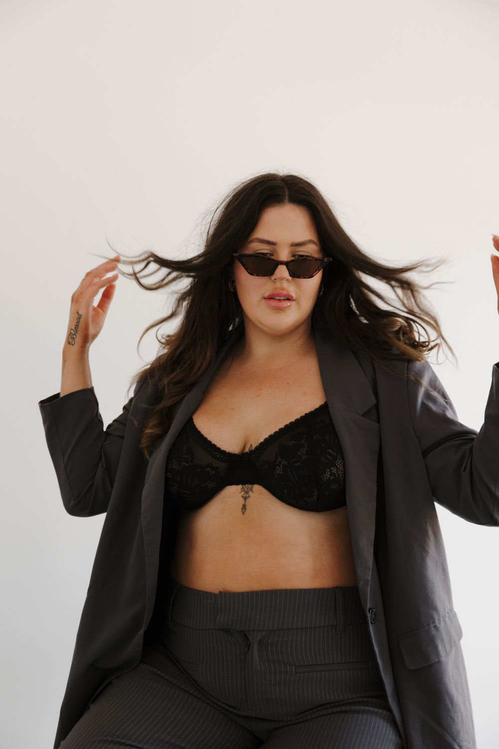 Model in black blazer and crop top strikes dynamic poses against white backdrop.