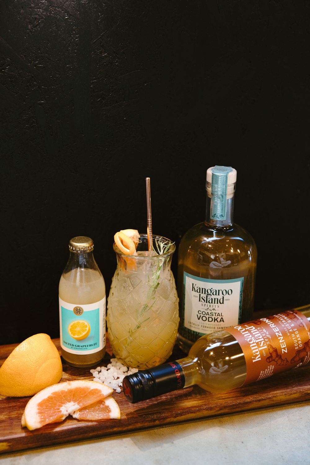 Collection of spirits and cocktail ingredients arranged on a rustic wooden surface.