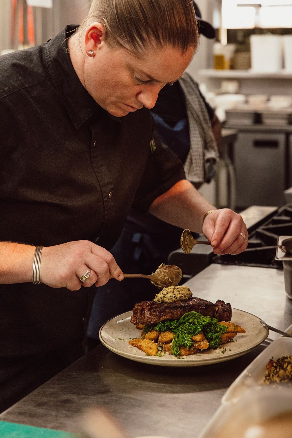 Chef plating and finishing dishes in a professional kitchen setting.