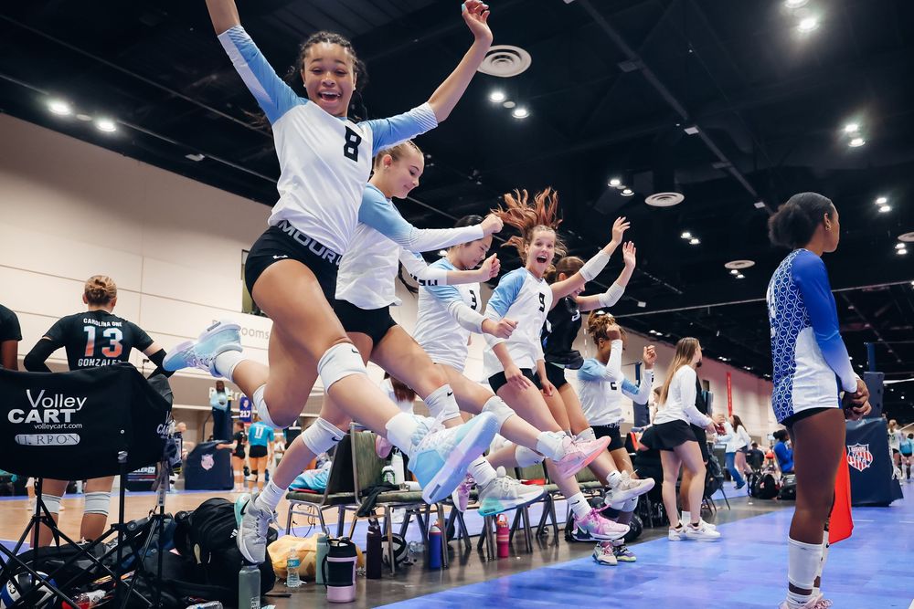 Athletes jumping in synchronized celebration during an indoor sports competition.