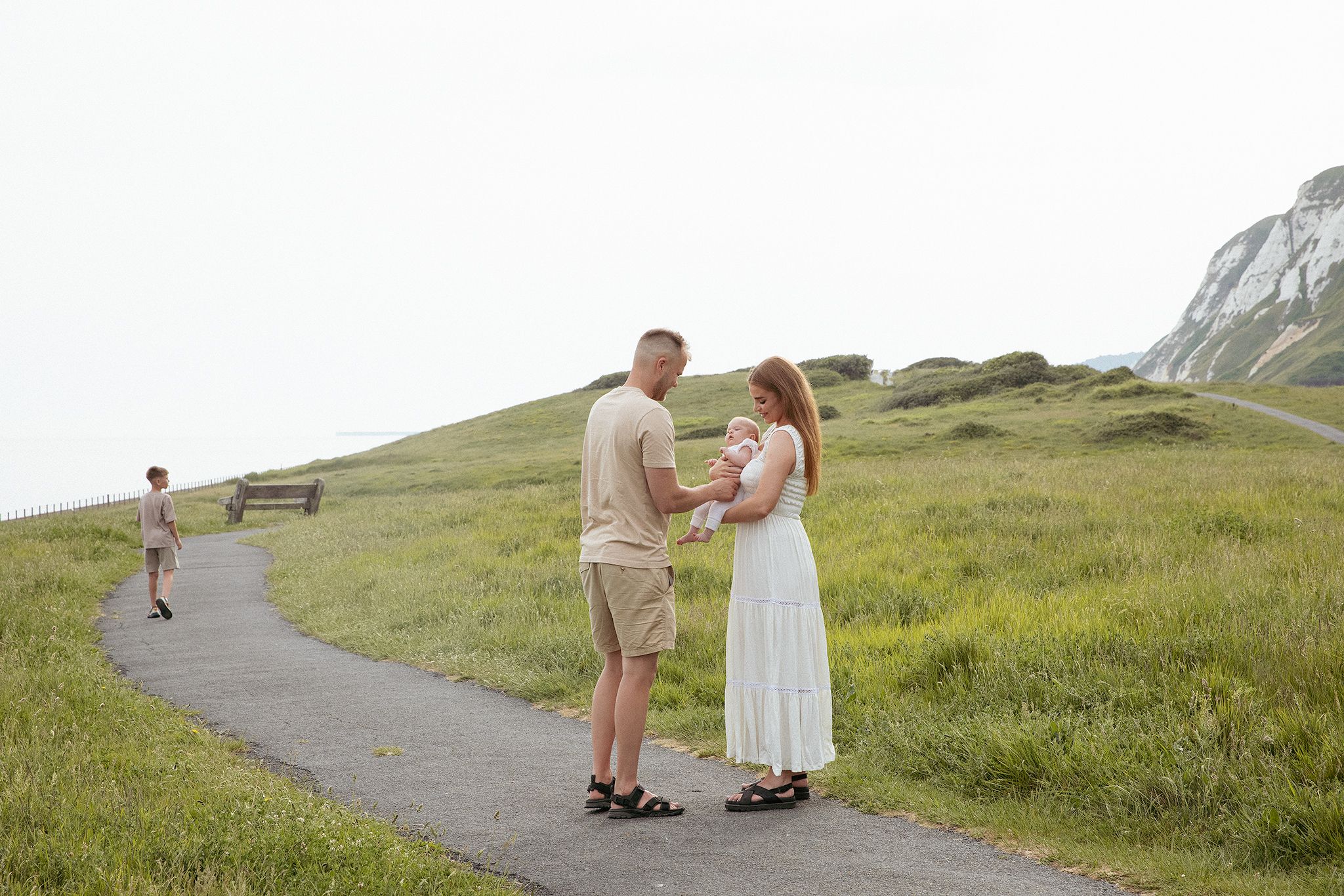 Outdoors family photography in Kent featuring a mother, father and son enjoying a playful moment near the White Cliffs of Dover.