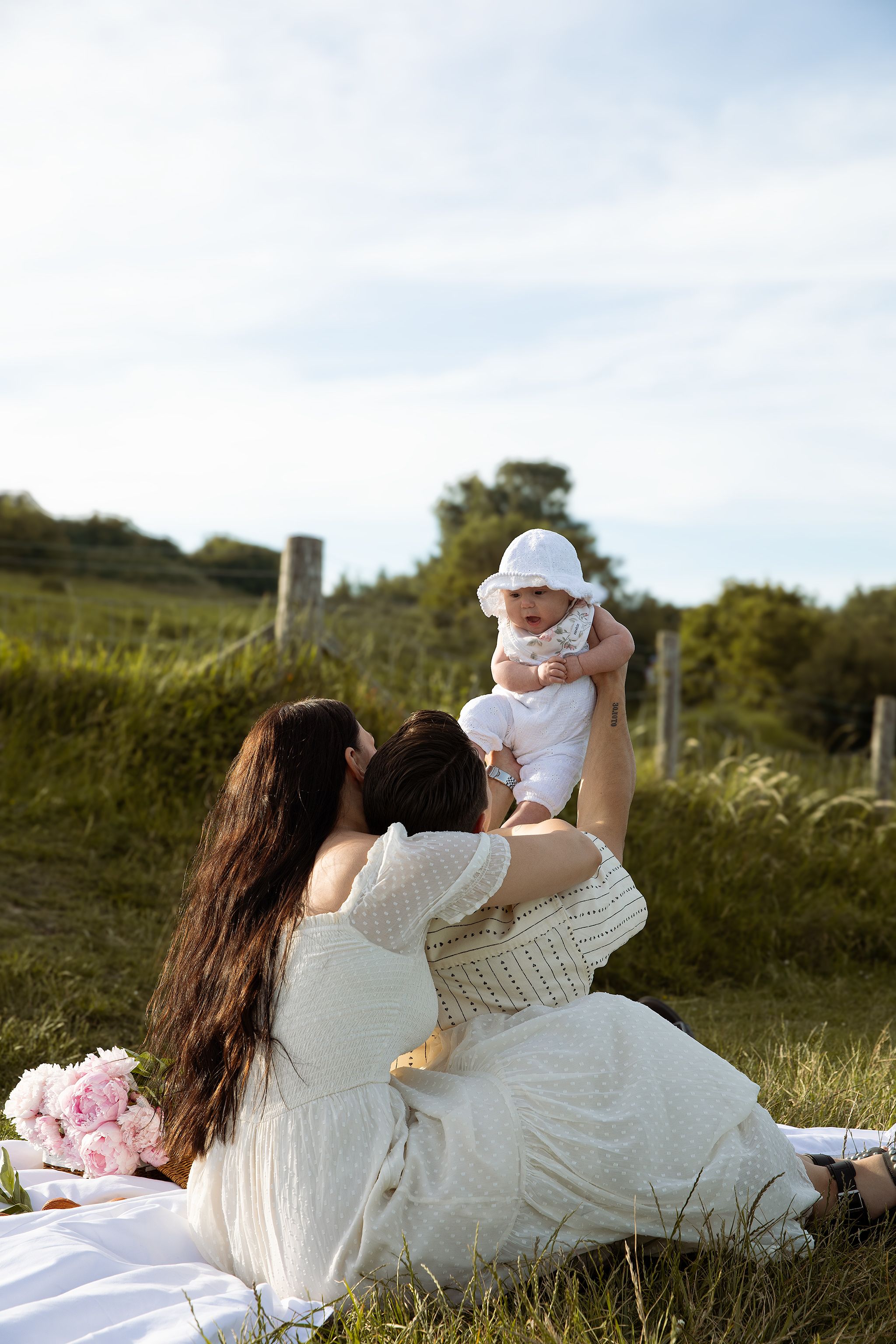 Cosy family photoshoot in Kent white cliffs featuring a newborn family enjoying themselves on a picnic photoshoot in golden hour.