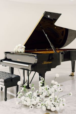 Black Blüthner grand piano decorated with white floral arrangements for a wedding.