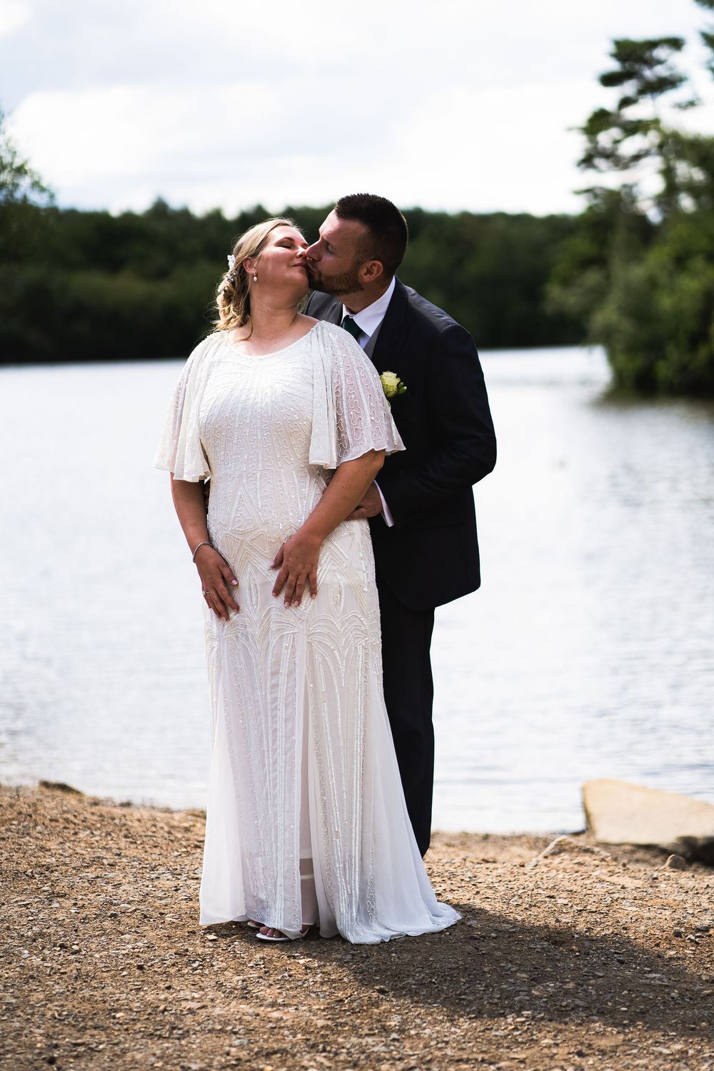 Romantic lakeside wedding couple sharing intimate moments on a beach shore in three similar poses.