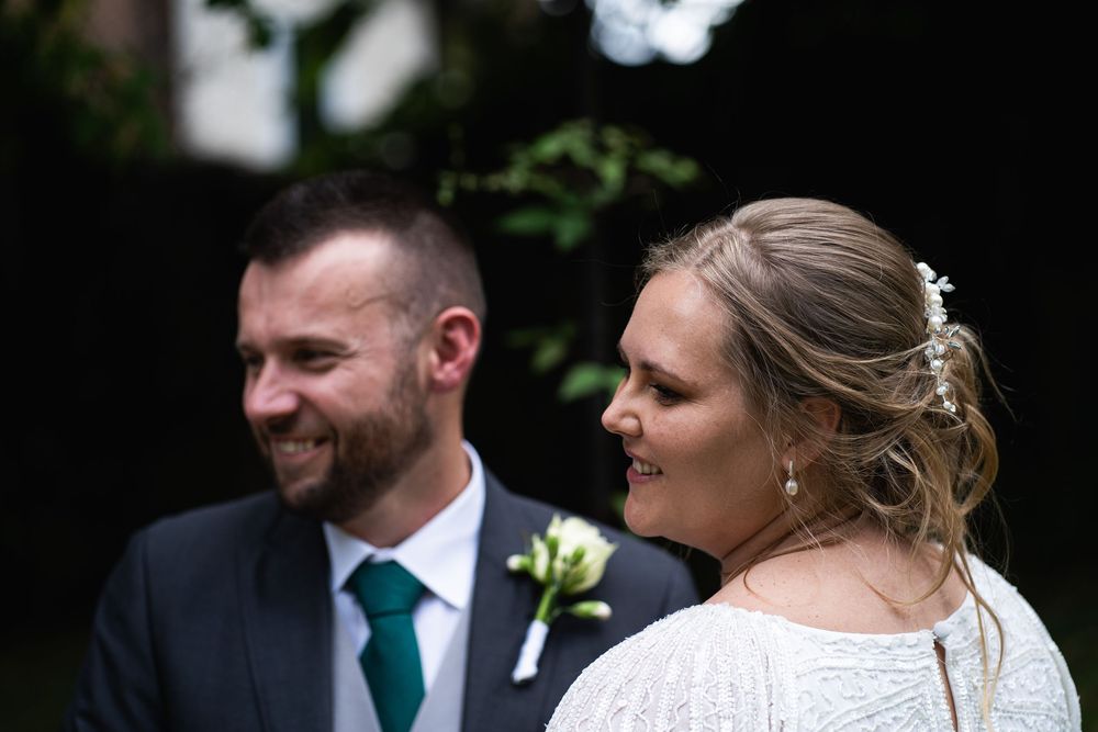 A joyful couple in wedding attire laugh together during their outdoor garden ceremony.