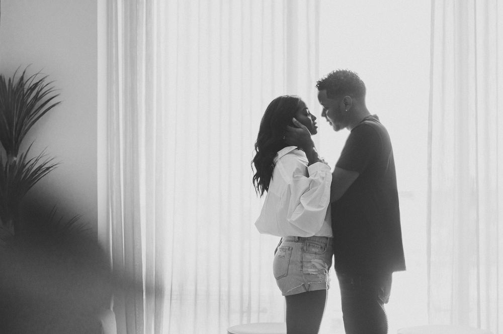Silhouettes of a couple in romantic poses against a white curtained backdrop.