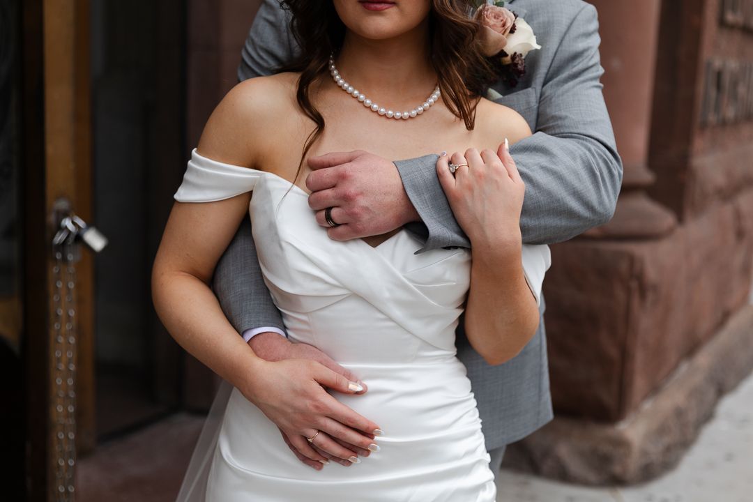 A Groom holds his bride as they look into the sunset over a reedy pond at the Pondview Wedding Venue in Central, MN