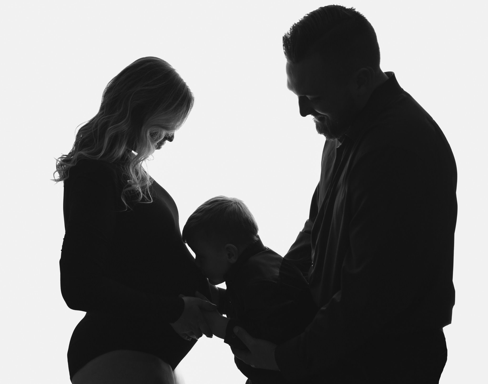 A beautiful back lit image with a big brother kissing his moms baby bump. Greenville SC newborn photographer. - Easley Sc newborn photograph
