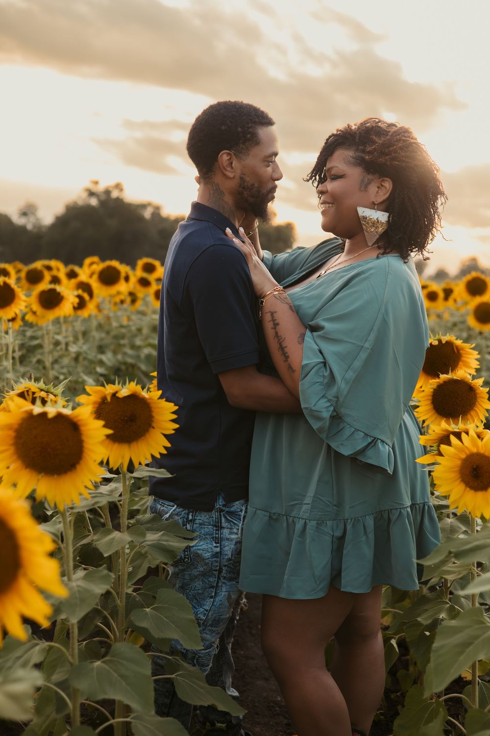 A romantic couple embraces in a stunning sunflower field at sunset creating a dreamy summer atmosphere.