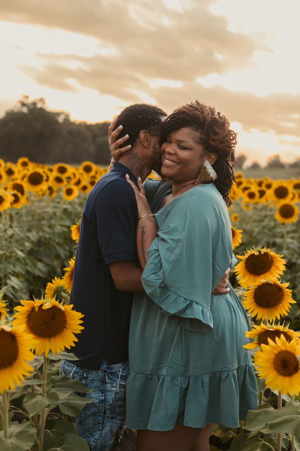 A romantic couple sharing an intimate moment in a sunflower field during golden hour sunset.