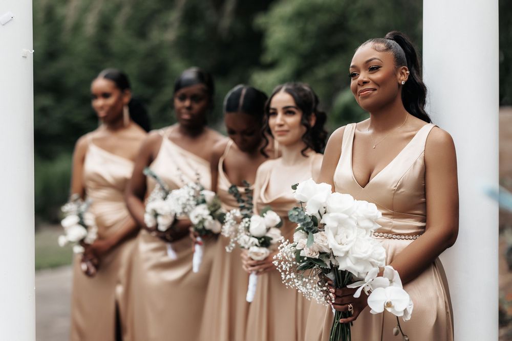Bridesmaids in blush pink dresses standing together, holding beautiful floral bouquets, exuding elegance and joy.