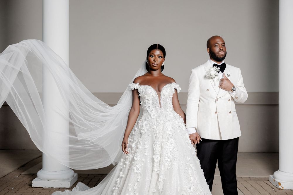 Elegant wedding portrait of a newlywed couple standing gracefully, the bride’s flowing veil adding a dreamy, romantic effect.