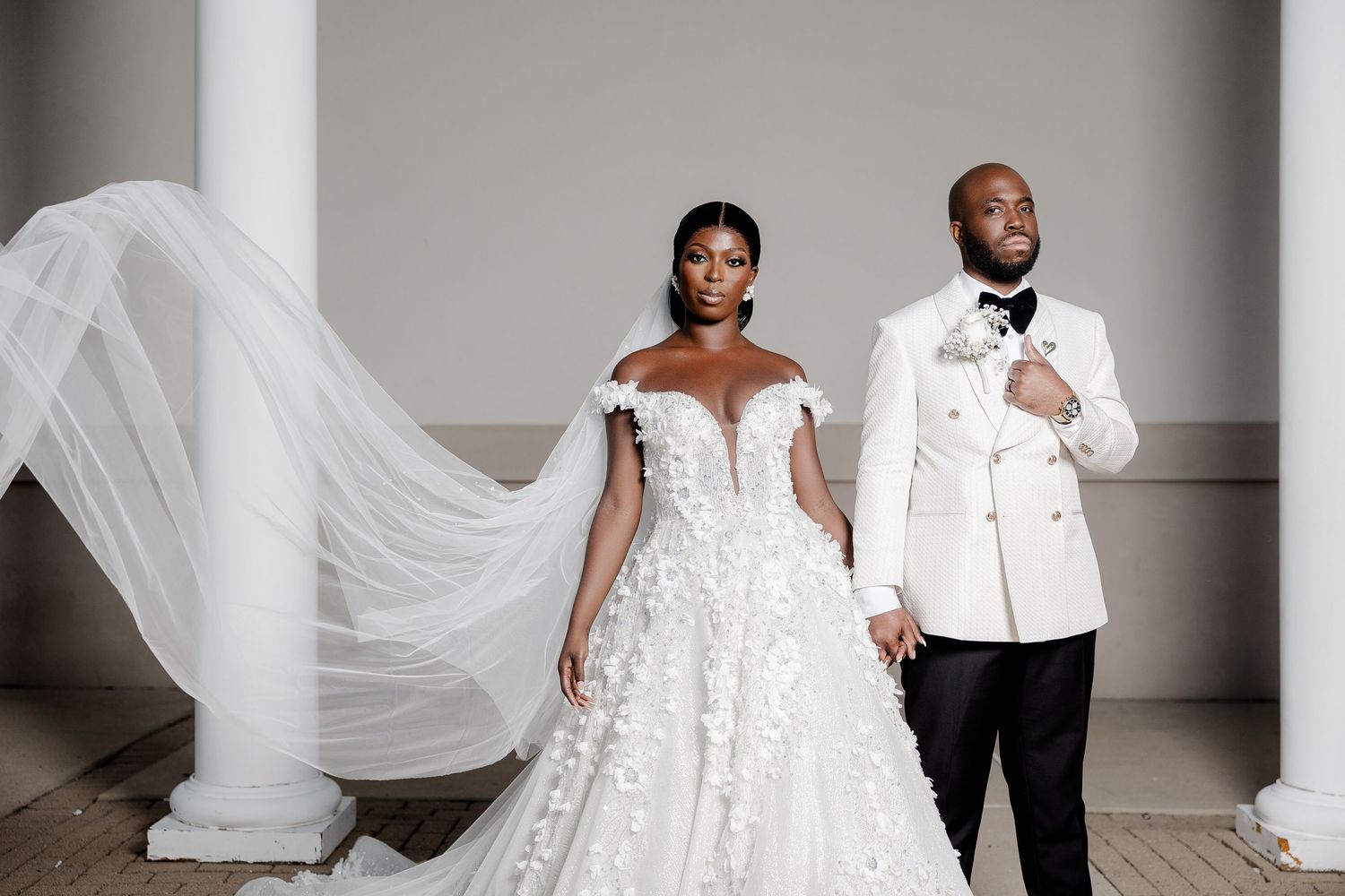 Elegant wedding portrait of a newlywed couple standing gracefully, the bride’s flowing veil adding a dreamy, romantic effect.