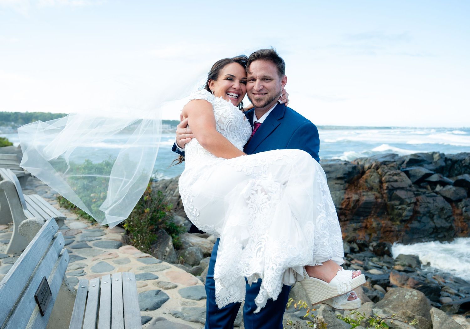 A seaside wedding photoshoot featuring a flowing white dress against rocky coastal backdrop.